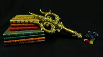 Trishula sacré doré présenté sur des livres