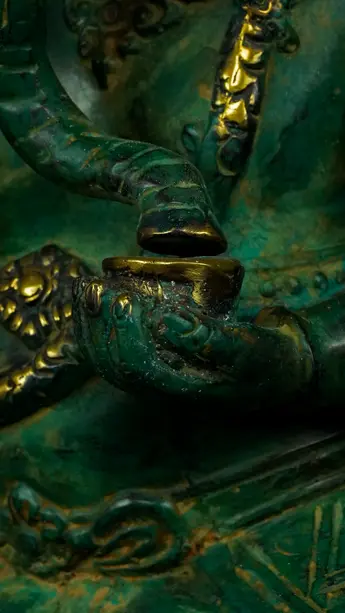 Détail de la main de Ganesh vert tenant un objet rituel