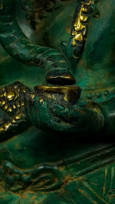 Détail de la main de Ganesh vert tenant un objet rituel